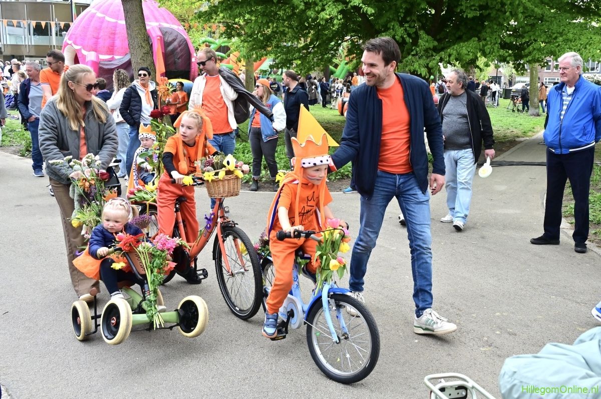 Jongen met een grote kroon op zijn fiets tijdens het kinderbloemencorso